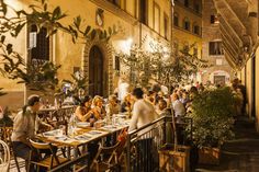 people are sitting at tables in an alleyway with stairs leading up to the building