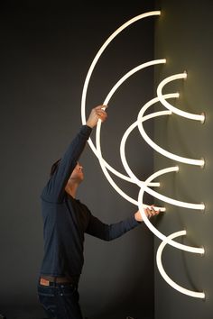 a man that is standing in front of a wall with some lights on it's sides