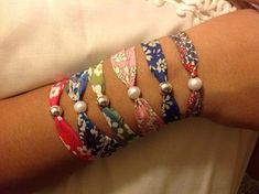 a woman's arm with bracelets and pearls on the wrist, all in different colors