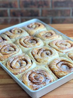 a pan filled with cinnamon rolls sitting on top of a wooden table