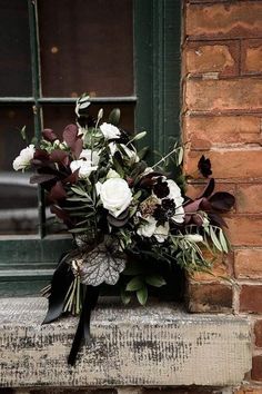 a bouquet of flowers sitting on top of a window sill in front of a brick building