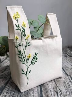 a white bag with yellow flowers embroidered on the side and green leaves in the back