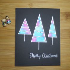 a christmas card with three trees on it and a teddy bear next to the card