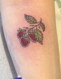 a close up of a person's leg with a tattoo on it and berries