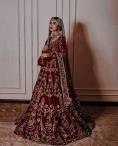 a woman in a red and gold bridal gown posing for the camera with her hands on her hips