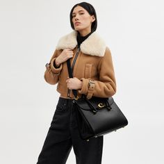 Our Broome has all the effortless cool of its namesake Soho street. The spacious foldover silhouette is crafted of luxe refined leather with a high shine finish and secures with our pushlock “C” closure. Featuring pockets inside and out for easy organization and room for a 16” laptop carry it by hand or use the detachable strap to wear it crossbody. | Coach Broome Carryall Bag 36 - Women's - Brass/black Soho Street, Easy Organization, Carry All Bag, New Handbags, Coach Handbags, Soho, Purses And Handbags, Fashion Beauty, Women Handbags