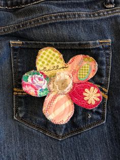 the back pocket of a pair of jeans with flowers on it, and an embroidered patch