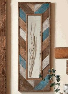 a mirror hanging on the wall next to a shelf with flowers and other items in it