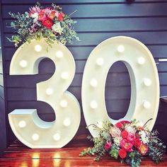 the number 30 is decorated with flowers and lights