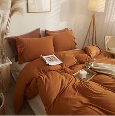 a bed with an orange comforter and pillows