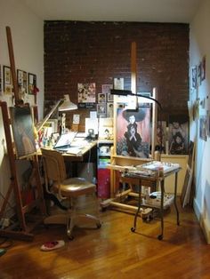 an artist's studio with lots of art work on the walls and wooden floors