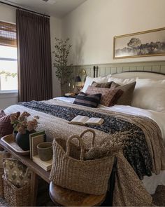 a bedroom with a large bed and baskets on the table in front of it's headboard