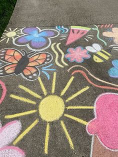 the sidewalk is painted with chalk and has flowers, butterflies, and sunbursts on it