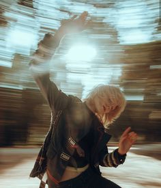 a woman with blonde hair is dancing in front of a light that is shining down on her