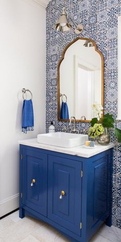 a bathroom with blue and white tiles on the walls, sink and mirror in it