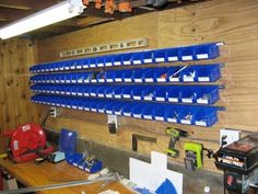 there are many blue bins on the wall in this garage with tools hanging from it