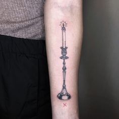 a woman's arm with a tattoo on it and a candle in the middle