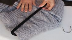 a person is holding the end of a knitted sweater with one hand on it