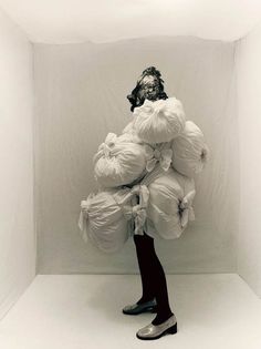 a woman standing in front of a white wall with bags on her head and legs