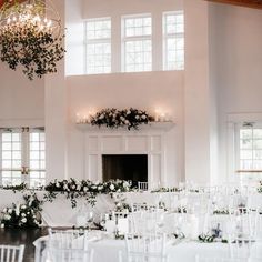 a room filled with lots of tables covered in white cloths and chairs next to a fireplace