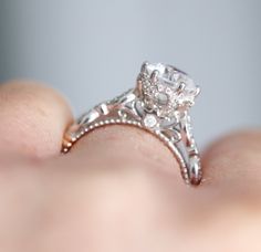 a close up of a person's hand holding an engagement ring