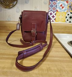 Very nice Coach Camera bag in burgundy leather 8 n h x 6 n w x 2.5 in deep with crossbody strap that has a shoulder protector. Inside has a zippered pocket with brown fabric interior and gold tone hardware. This style is hard to find and this one is in good condition. Coach Camera Bag, Hazel Green, Brown Fabric, Crossbody Strap, Hard To Find, Cross Body Handbags, Purses And Handbags, Camera Bag, Crossbody Bags