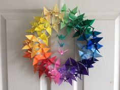 an origami wreath made out of colored paper is hanging on the front door