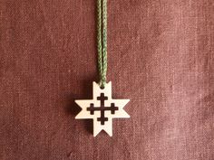 a wooden ornament hanging from a green string on a brown cloth with an arrow in the center