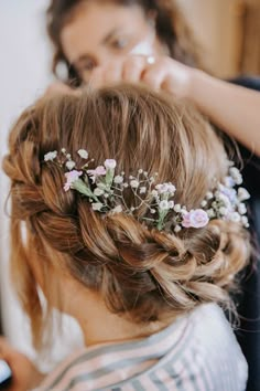 a woman is getting her hair done with flowers