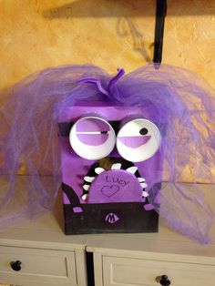 a purple bag with googly eyes sitting on top of a dresser