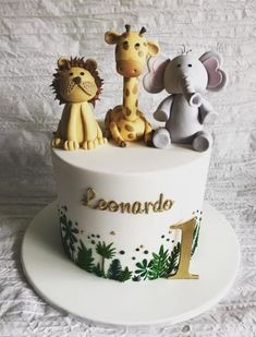 a white cake topped with three different types of animals and the number one on it