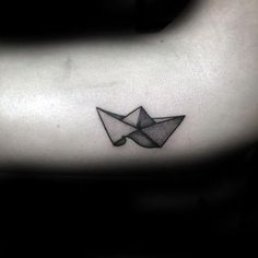 a black and white photo of an origami paper boat tattoo on the arm