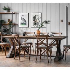 a dining room table with chairs and pictures on the wall in the backround