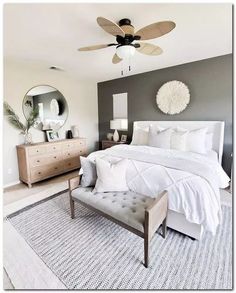 a white bed sitting in a bedroom next to a dresser and mirror on top of a rug