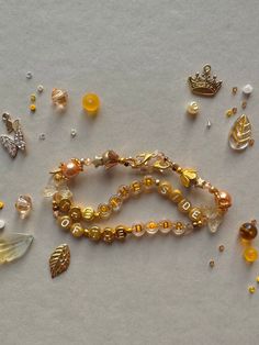 some beads and other items are laying on the table together, including a necklace with gold leaves