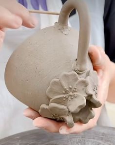 a person is holding a clay pot with flowers on it and the handle has been made