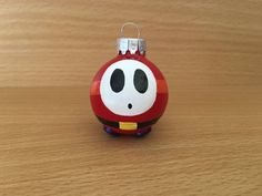 a red ornament with a black face on it sitting on a wooden surface