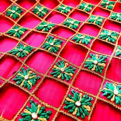 some green and gold decorations on a red cloth with pearls in the center, sitting on top of a table