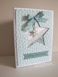 a white card with a blue bow on the front, and a merry christmas message below it