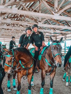 two women are sitting on horses in the stable