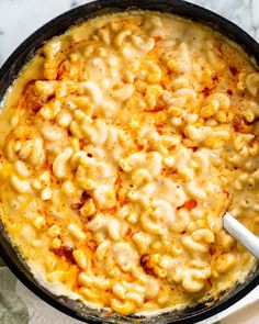 a skillet filled with macaroni and cheese on top of a marble counter