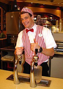 a man wearing an apron and bow tie standing in front of two salt shakers