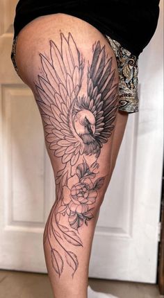 a woman's thigh with flowers and a bird tattoo on the side of her leg