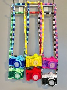 three lego cars are hanging on a wall with colorful bead necklaces attached to them