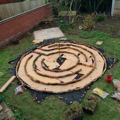 a circular garden design made out of wood and bricks in the middle of a yard