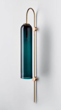 a green glass bottle hanging on the wall next to a metal pole with a handle