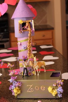 there is a doll house on top of a table with flowers and hearts hanging from the ceiling