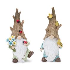 two statues of gnomes sitting next to each other near a tree trunk with flowers on it