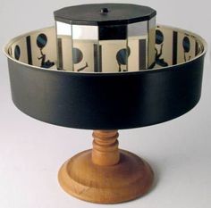 a black and white cake plate sitting on top of a wooden stand next to a mirror