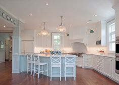 a large kitchen with white cabinets and wooden floors